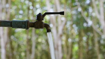 Hand off water valve with blur background of green nature, water saving concept, Hand close water valve to stop water drop from faucet, Energy conservative