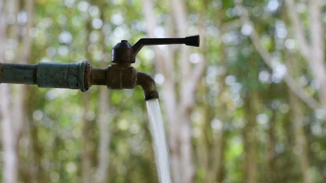 Hand off water valve with blur background of green nature, water saving concept, Hand close water valve to stop water drop from faucet, Energy conservative