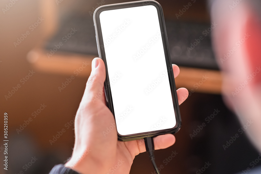 Poster Man hand holding smartphone and use device and charging device while using with blank white screen for mockup
