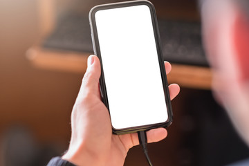 Man hand holding smartphone and use device and charging device while using with blank white screen for mockup