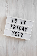 'Is it friday yet?' words on a lightbox on a white wooden surface, top view. Overhead, from above, flat lay.