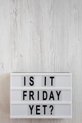 'Is it friday yet?' words on a modern board on a white wooden background, top view. Overhead, from above, flat lay. Space for text.