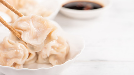 Fresh, delicious boiled pork, shrimp gyoza dumplings on white background with soy sauce and chopsticks, close up, lifestyle. Homemade design concept.