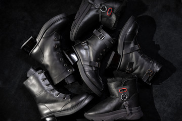 Fototapeta na wymiar set of black leather boots with buckles and laces on a dark background.