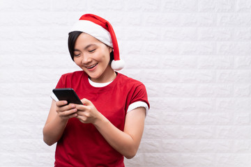 Happy woman woman wearing santa hat and use smart phone