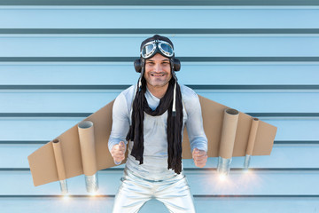 man in silver suit with glasses and aviator helmet and cardboard plane wings
