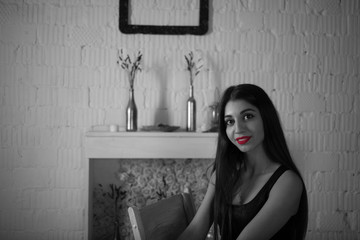 black and white noir portrait of elegant lady with red lips. brunette woman in black dress against the background of an interior with white walls © Konstantin