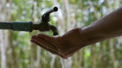 Hand off water valve with blur background of green nature, water saving concept, Hand close water valve to stop water drop from faucet, Energy conservative