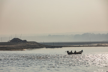 Early morning scene of a silhouetted couple in a small boat on the Irrawaddy river, Myanmar.