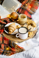 Simple country home breakfast in bed, coffee with milk and homemade pastry on plaid blanket
