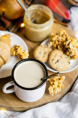 Simple country home breakfast in bed, coffee with milk and homemade pastry on plaid blanket