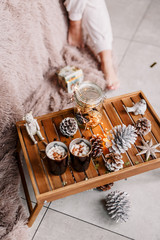 Table with a cup on the bed, marshmallow and Christmas cookies, cozy knitted blanket. New Year 2020, flat lay. Christmas composition with a cup tray and a mug