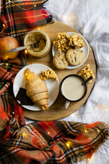 Simple country home breakfast in bed, coffee with milk and homemade pastry on plaid blanket