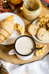 Simple country home breakfast in bed, coffee with milk and homemade pastry on plaid blanket