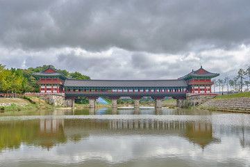 Fototapeta premium Scenic view of Woljeonggyo Bridge over Hyeongsan River in Gyeongju in South Korea. Beautiful summer cloudy look of colorful traditional asian style bridge over creek in Republic of Korea.
