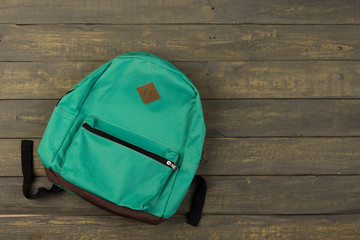 Back to school concept - blue backpack on wooden backgroung,