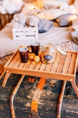 Table with a cup on the bed, marshmallow and Christmas cookies, cozy knitted blanket. New Year 2020, flat lay. Christmas composition with a cup tray and a mug
