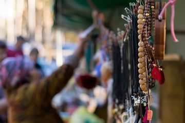 Naklejka premium beads and jewelry hang on the street in the Asian market against the background of sellers and buyers who choose the goods