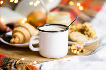 Simple country home breakfast in bed, coffee with milk and homemade pastry on plaid blanket