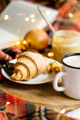 Simple country home breakfast in bed, coffee with milk and homemade pastry on plaid blanket