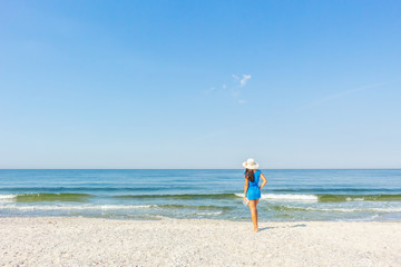 young, beautiful girl in a bikini and hat on the beach