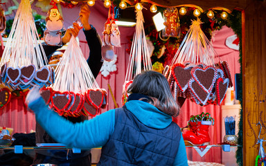 Woman at Gingerbread cookies food on Christmas market in Europe in winter. German Night street Xmas...