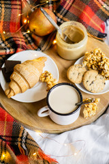 Simple country home breakfast in bed, coffee with milk and homemade pastry on plaid blanket