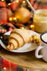 Simple country home breakfast in bed, coffee with milk and homemade pastry on plaid blanket