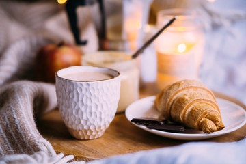 Cozy winter weekend breakfast, coffee and croissant on wooden tray