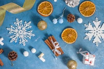 Christmas and New Year pattern made of snowflakes,cookies, cinnamon, orange, cones and marshmallows on a blue background with stars. Christmas, winter, new year concept. Flat lay, top view, copy space