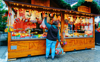 Woman with Gingerbread cookies food on Christmas market in Europe in winter. German Night street...