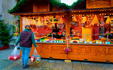 Obraz premium Woman with Gingerbread cookies food on Christmas market in Europe in winter. German Night street Xmas and holiday fair in European city or town, December. Kaiser Wilhelm Memorial Church in Berlin