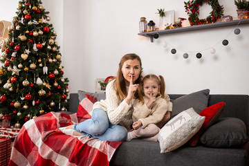 mother and little girl relax playing near Christmas tree on Christmas eve at home
