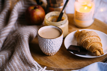 Cozy winter weekend breakfast, coffee and croissant on wooden tray