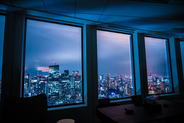 夜のオフィスと東京の街並み