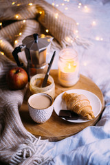 Cozy winter weekend breakfast, coffee and croissant on wooden tray