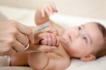 Obraz na płótnie Canvas Mother cuts baby nails with a scissors. Caucasiafn family