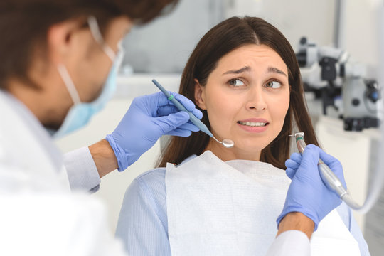 Scared woman at dental office, looking panickly at dentist