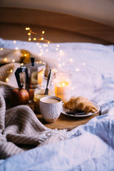 Obraz na płótnie Canvas Cozy winter weekend breakfast, coffee and croissant on wooden tray