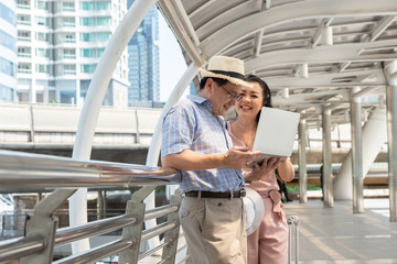 Fototapeta premium Couple Using Laptop While Standing On Bridge In City