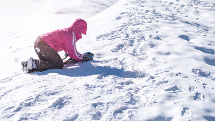 Fototapeta na wymiar Asia Kid girl in snowsuit playing on snow floor at ski resort in Japan in winter season.