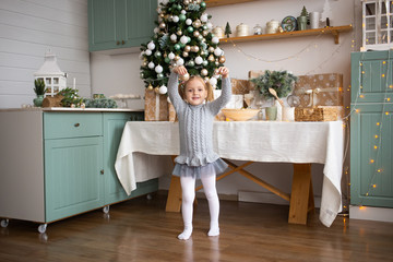Fototapeta na wymiar happy little girl having fun with Christmas tree toy in kitchen