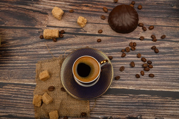 Cup of coffee, the marshmallows in chocalate, brown sugar and coffee beans on wooden background. Close up.