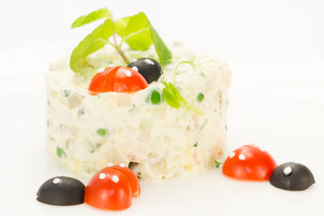 Olivier salad decorated with tomatoes on a white background restaurant