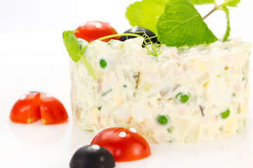 Olivier salad decorated with tomatoes on a white background restaurant