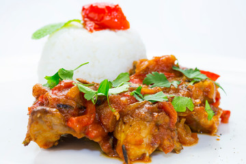 Chinese chicken in sweet and sour sauce with rice on a white plate in a restaurant.
