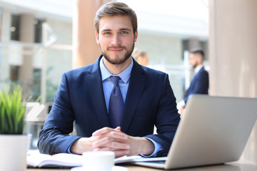 Portrait of young man sitting at his desk in the office.