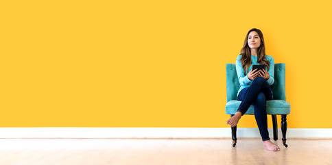Young woman holding a tablet computer in a yellow wall room