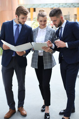 Fototapeta premium Three young businessmen standing discussing business at an office meeting.