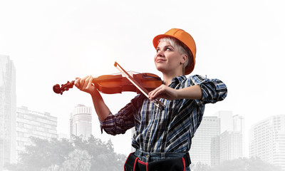 Naklejka premium Beautiful woman in safety helmet playing violin